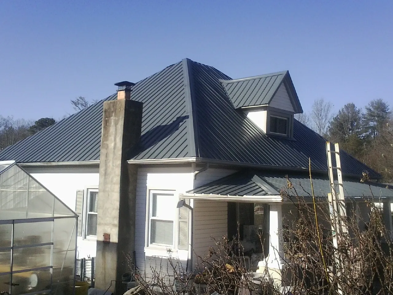 Dark blue standing seam metal roof on a white farmhouse with dormer — Slate & Tile Roof Repair by Roofing Brothers in Sparks Glencoe