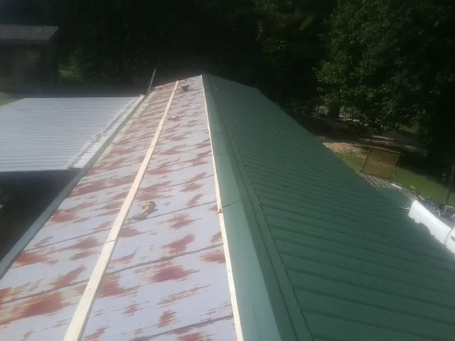 Old rusted panels beside newly installed green metal roofing — Wind Damage Roof Repair by Roofing Brothers in Sparks Glencoe
