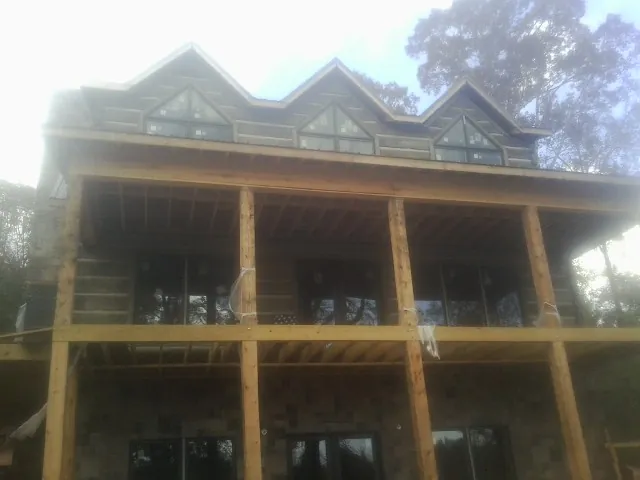 Dormers and porch framing on a large log home under construction — Roof Coating work by our crew in Sparks Glencoe