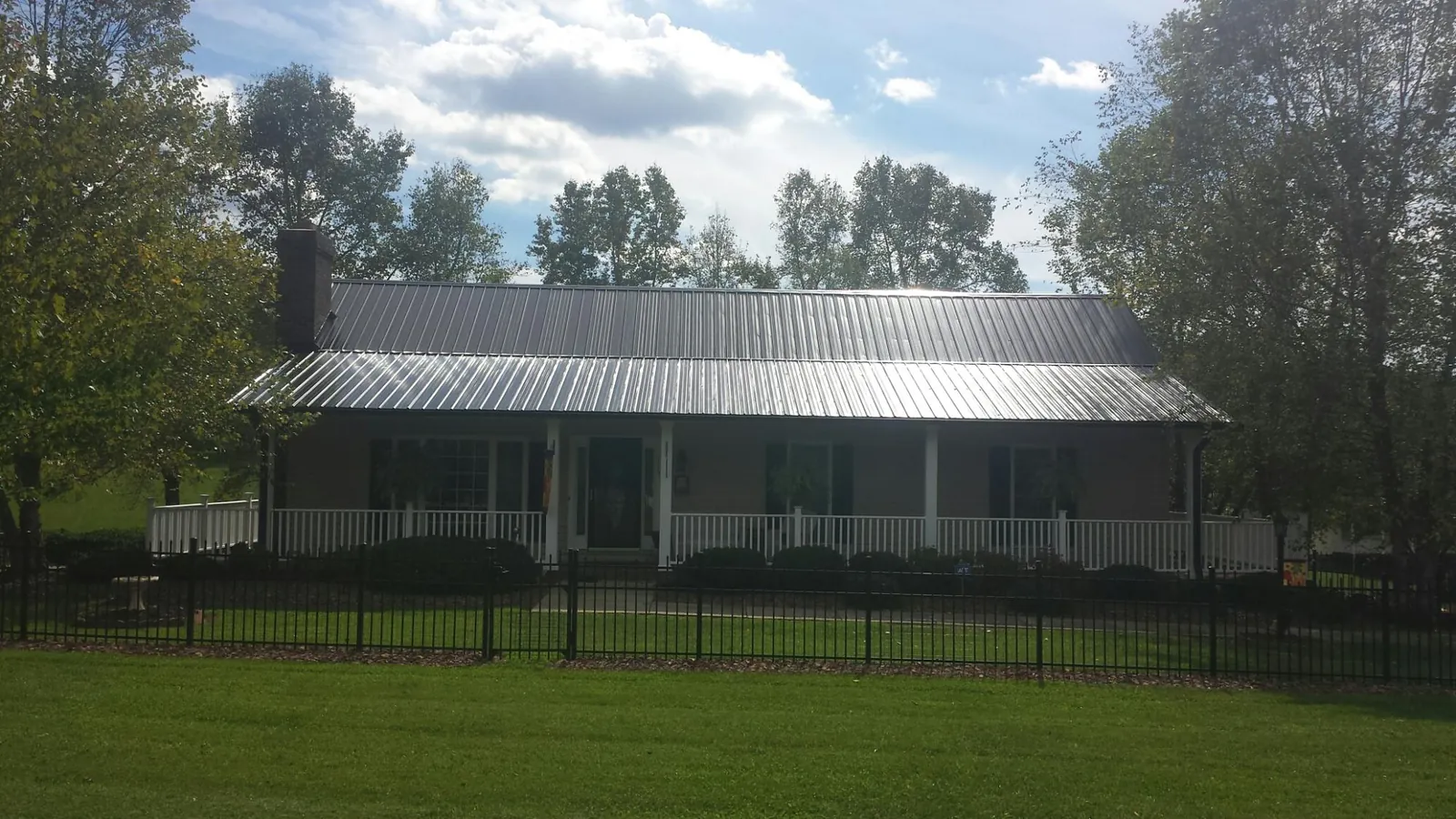 Gray metal roof on a brick ranch with a full width front porch — Gutter Guard Installation work by our crew in Sparks Glencoe