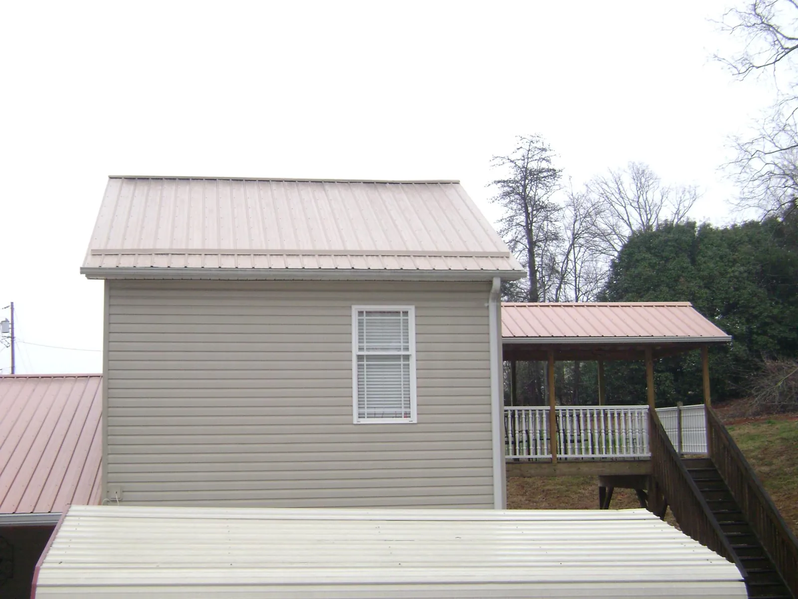 Tan metal roofs on a two story addition and attached porch, from a Roof Replacement job in Sparks Glencoe
